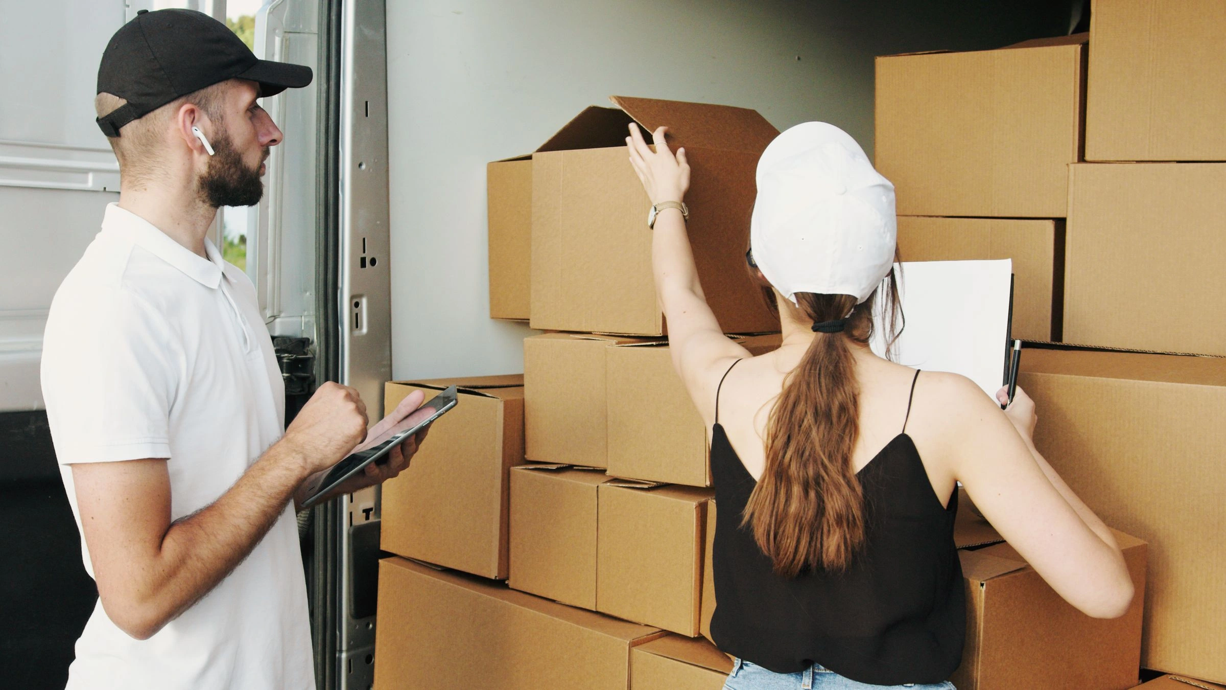 Couriers checking and organizing parcels in a delivery van
