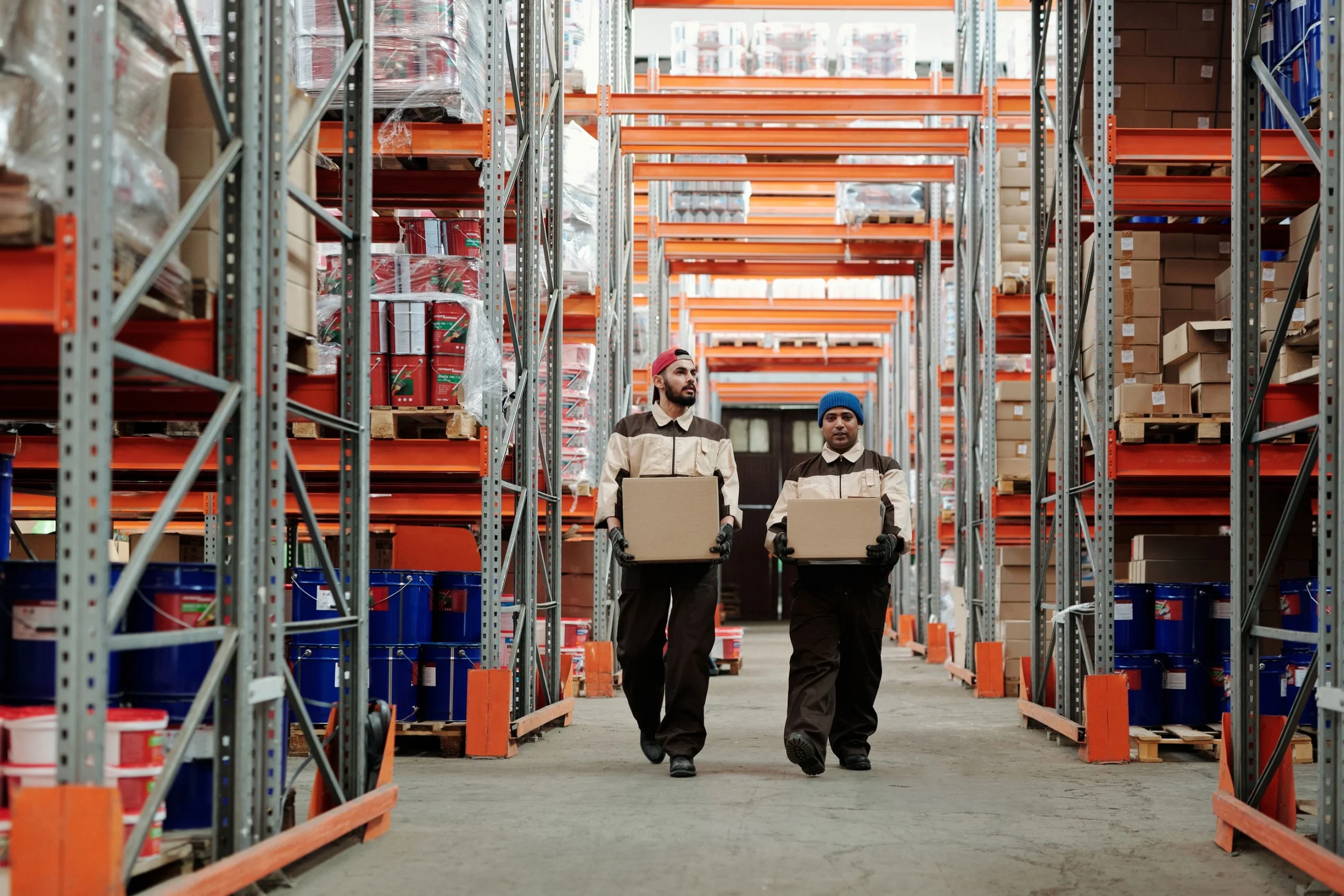 Workers carrying parcels through warehouse shelves